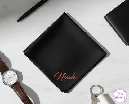 A personalized black cotton handkerchief with the name "Noah" custom-applied in a shimmering rose gold vinyl script.