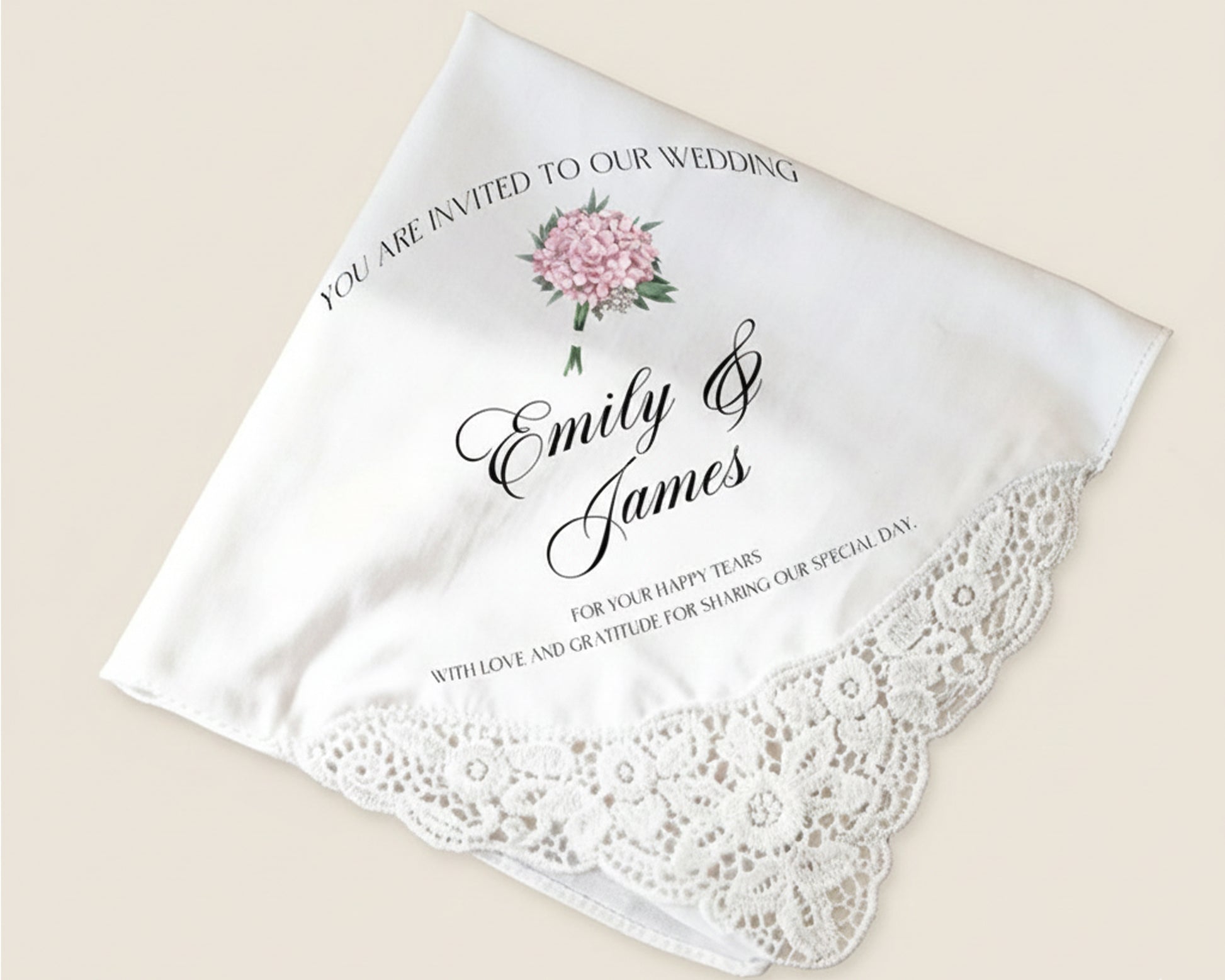 White handkerchief with lace edge, floral design, and wedding invitation text on a beige background.