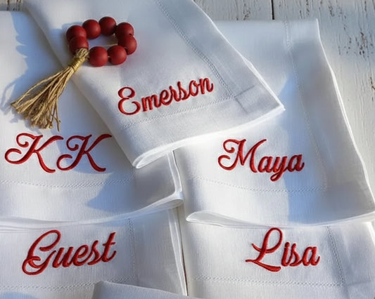 White napkins with red embroidered names on a wooden surface