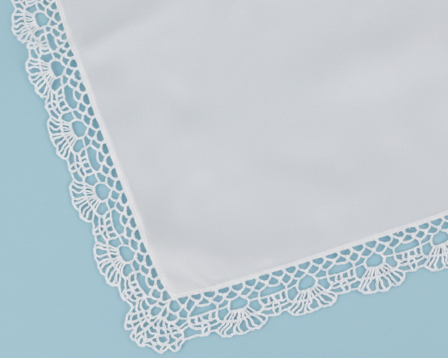 High resolution detail of a scalloped floral lace trim on a premium white cotton handkerchief.