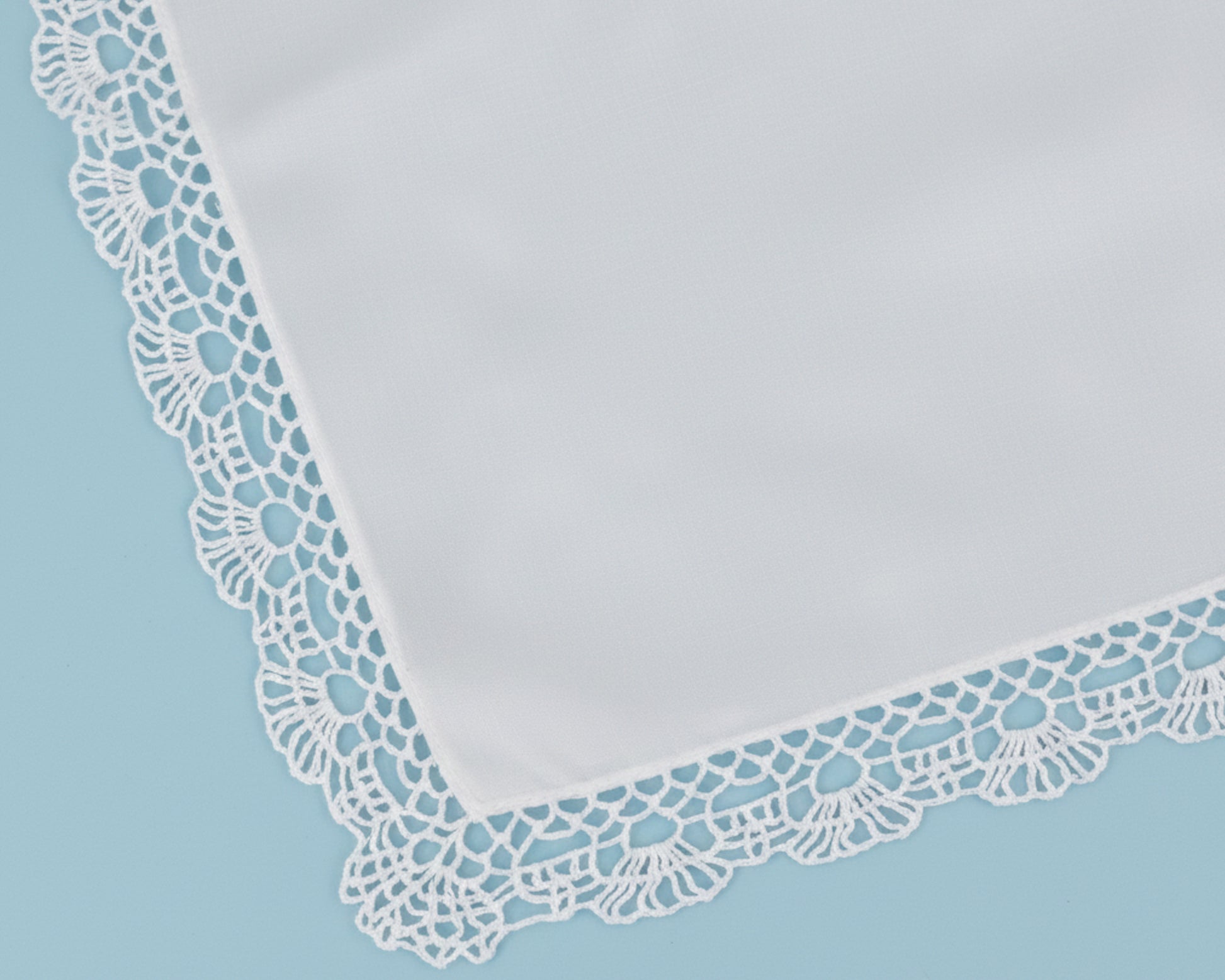 High resolution detail of a scalloped floral lace trim on a premium white cotton handkerchief.