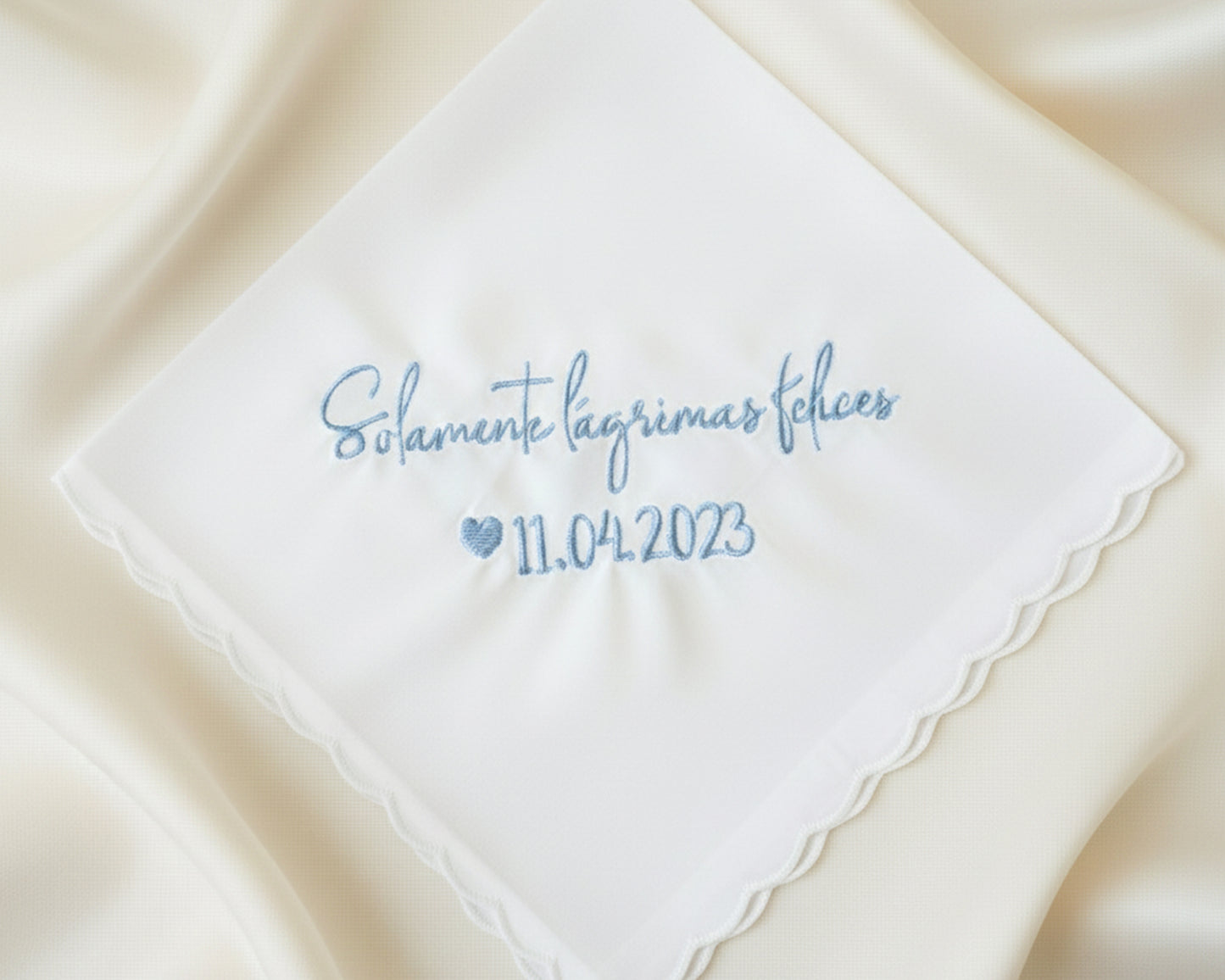 A customized 100% cotton handkerchief featuring the Spanish sentiment for happy tears and a wedding date, placed on a rustic dark wood surface.