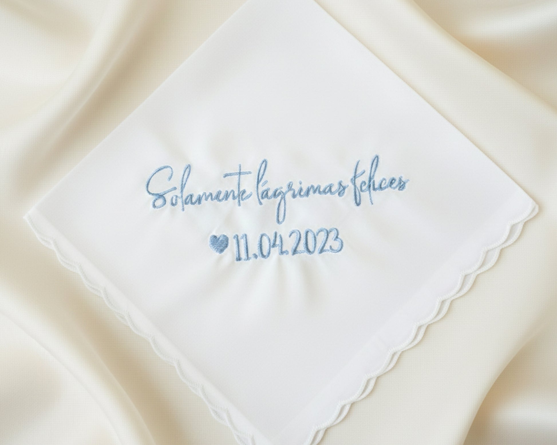 A customized 100% cotton handkerchief featuring the Spanish sentiment for happy tears and a wedding date, placed on a rustic dark wood surface.