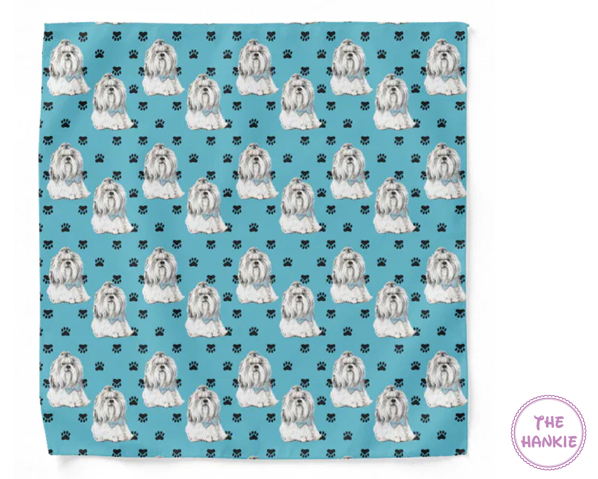 Patterned towel with white dogs and black paw prints on a blue background, featuring 'The Hankie' brand.