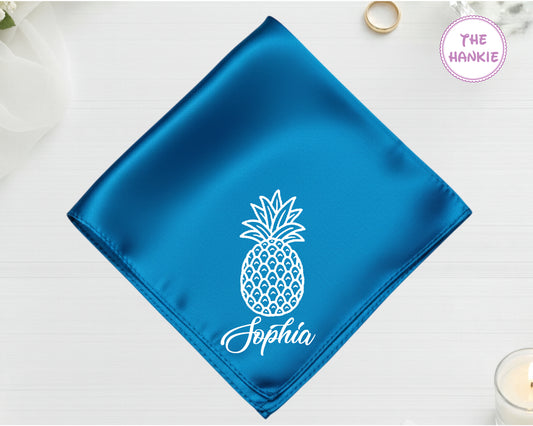 A brilliant sapphire blue satin handkerchief customized with the name "Sophia" and white embroidery of a detailed whole pineapple silhouette.
