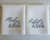 Two white pillows with embroidered names on a wooden surface