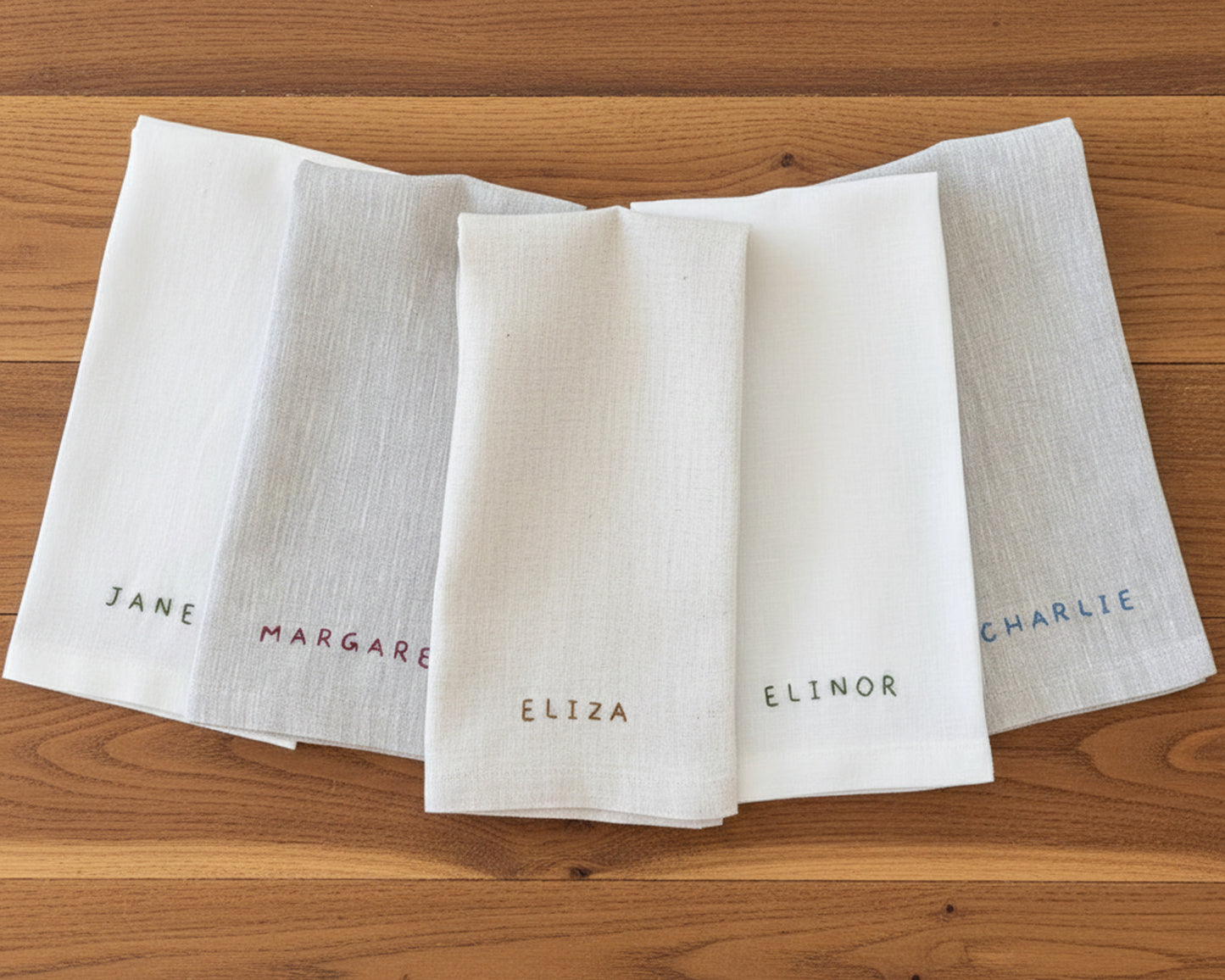 Two white cotton coasters showing the consistent stitching quality of machine-embroidered names "EDWARD" and "ELINOR".