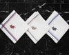 A white cotton handkerchief by U.S. Polo Assn. with gold striped borders and a royal blue embroidered brand logo.