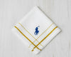 A white cotton handkerchief by U.S. Polo Assn. with gold striped borders and a royal blue embroidered brand logo.