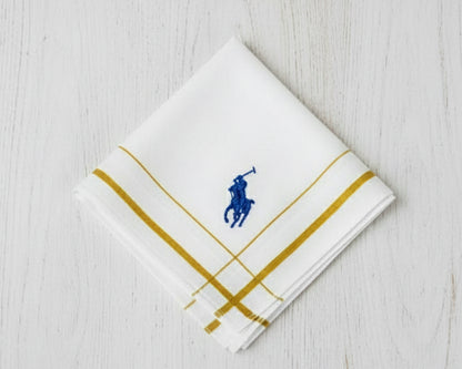 A white cotton handkerchief by U.S. Polo Assn. with gold striped borders and a royal blue embroidered brand logo.