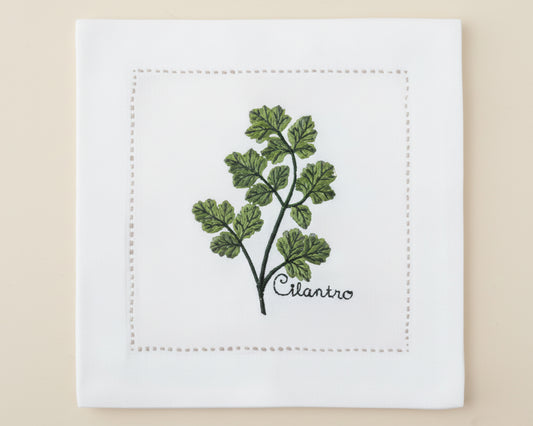 Single white linen cocktail napkin featuring a detailed green Basil branch embroidery with a delicate hemstitch border.