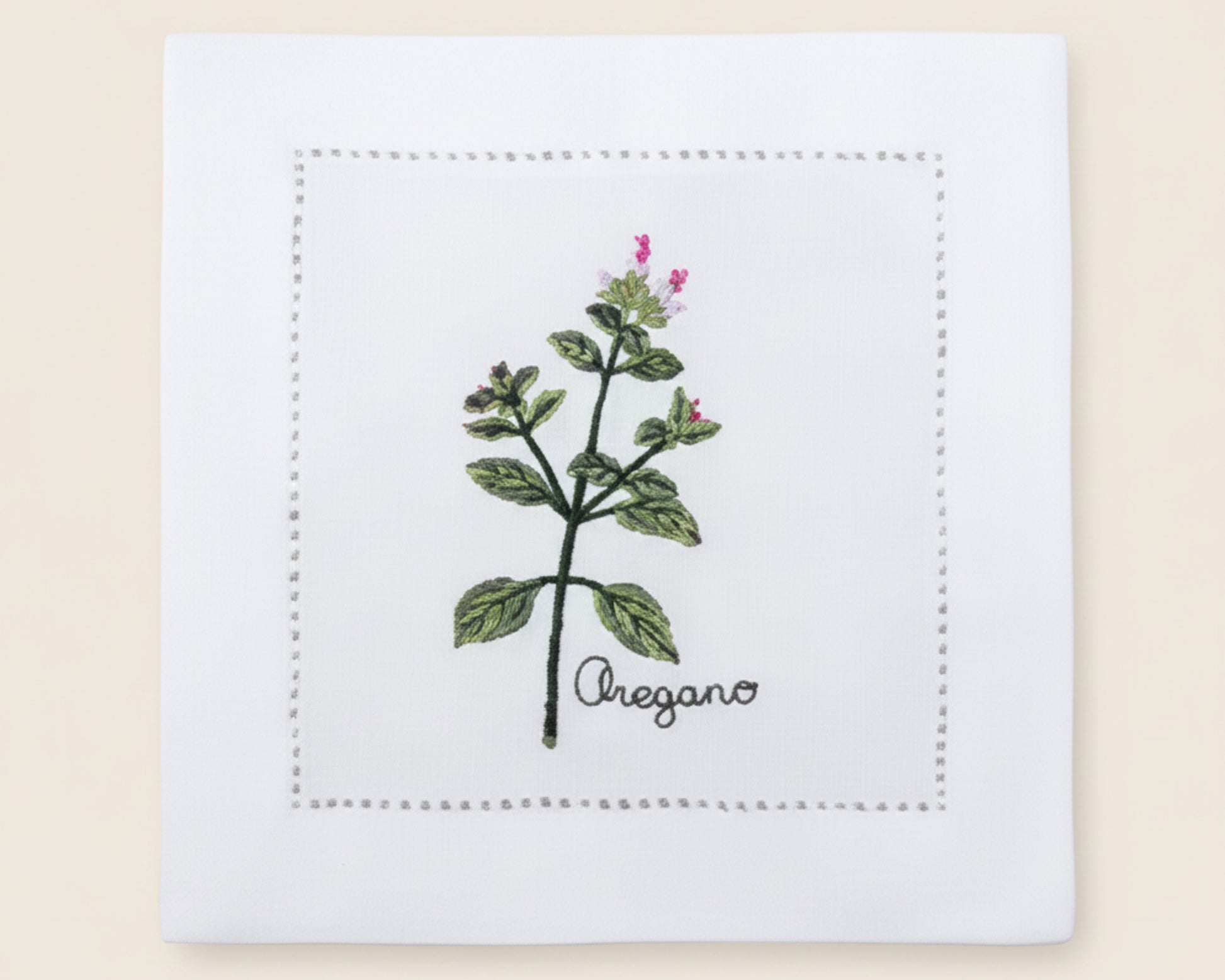 Single white linen cocktail napkin featuring a detailed purple-flowered Cardamom plant embroidery with a hemstitch border.