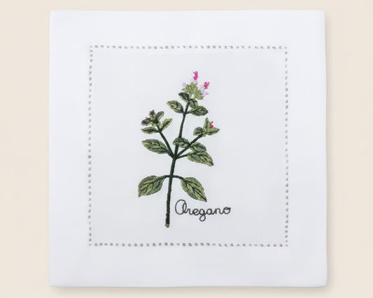 Single white linen cocktail napkin featuring a detailed purple-flowered Cardamom plant embroidery with a hemstitch border.