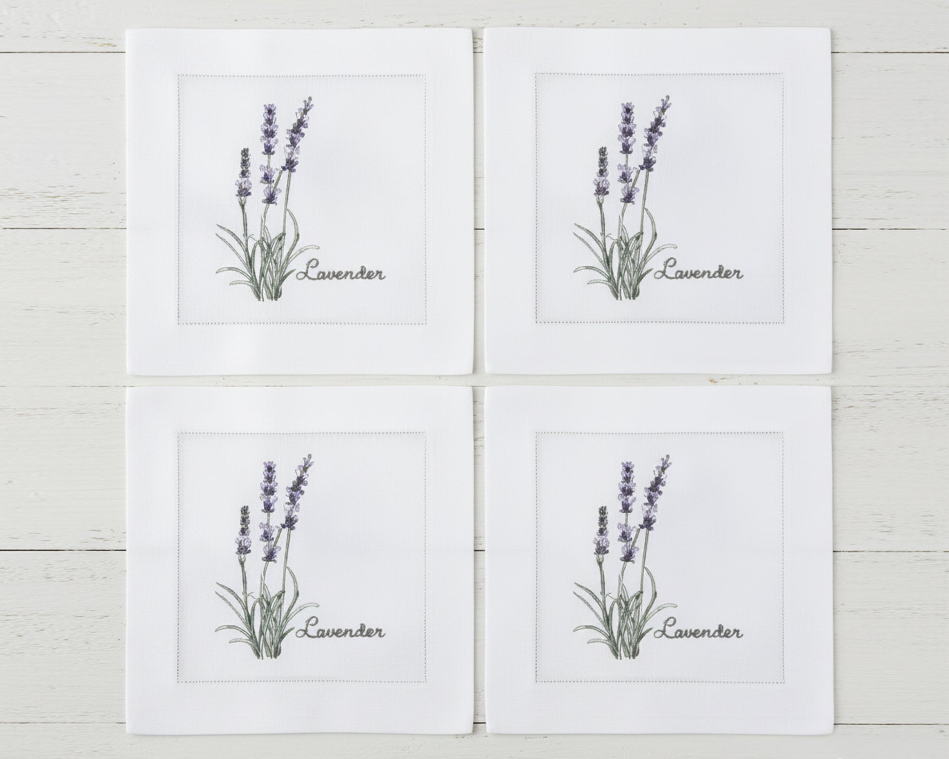 A set of four white linen cocktail napkins featuring embroidered Tarragon, Celery, Mustard, and Oregano botanical designs.