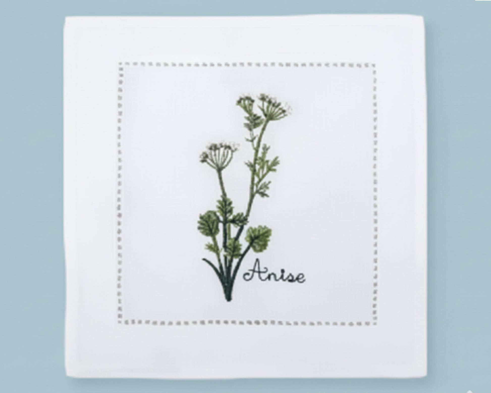 Single white linen cocktail napkin featuring a detailed yellow Dill flower embroidery and a decorative hemstitch perimeter.