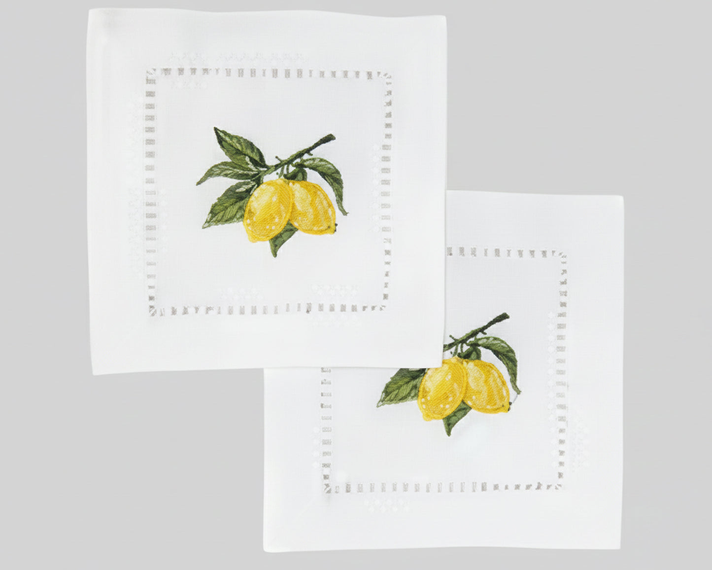 A fanned-out stack of VOICI lemon embroidered pure cotton napkins displayed on a light green background for modern bar styling.