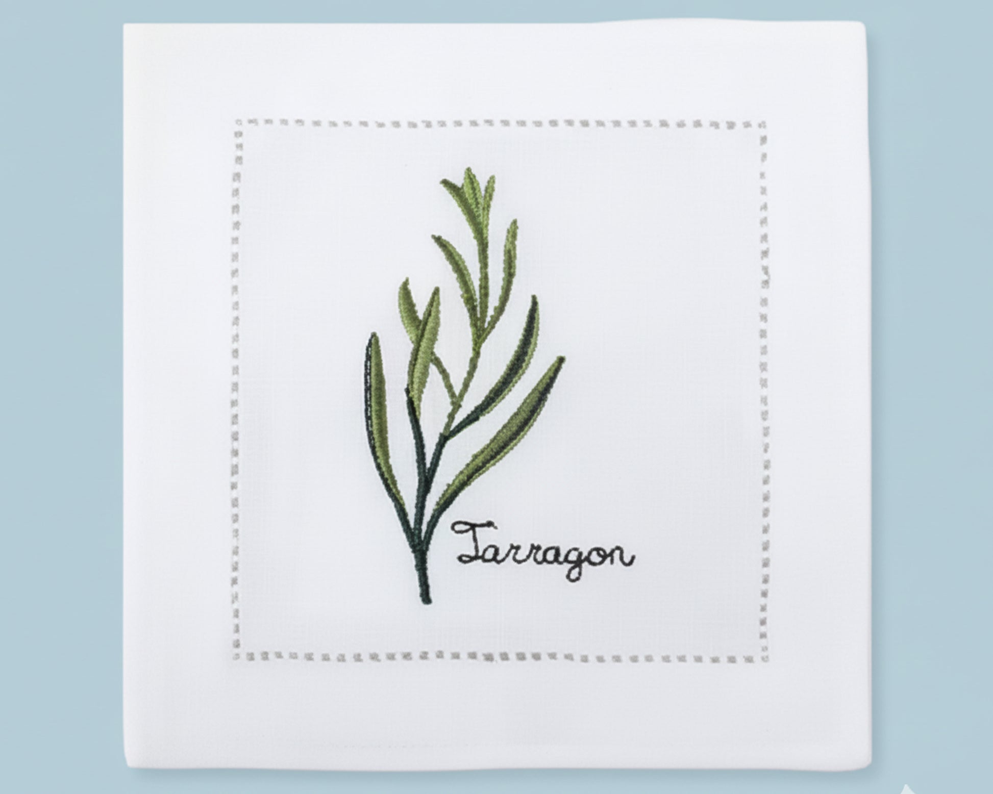 A stack of four white linen cocktail napkins featuring detailed yellow Mustard flower embroidery with a tailored hemstitch edge.