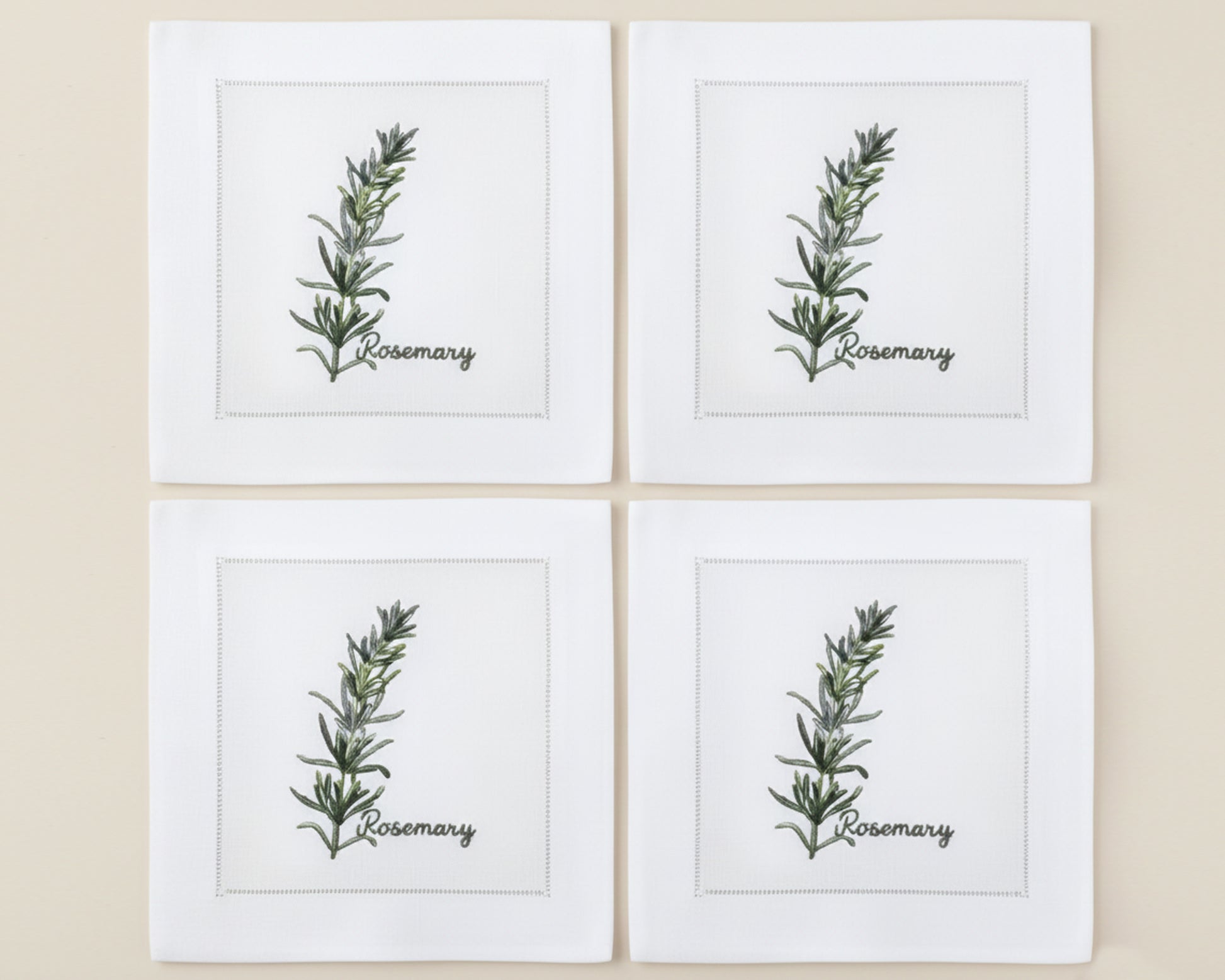 Single white linen cocktail napkin featuring a detailed purple-flowered Rosemary sprig embroidery with a hemstitch edge.