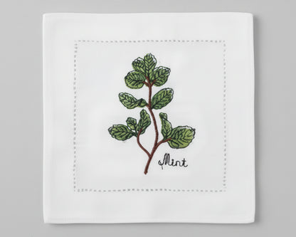 Single white linen cocktail napkin featuring a detailed purple-flowered Rosemary sprig embroidery with a hemstitch border.