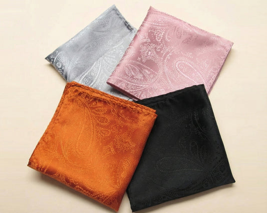 A collection of four men's satin paisley pocket squares in silver, copper, black, and rose gold.