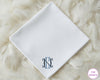 A classic white cotton handkerchief personalized with a sophisticated interlocking navy blue script monogram in the corner.