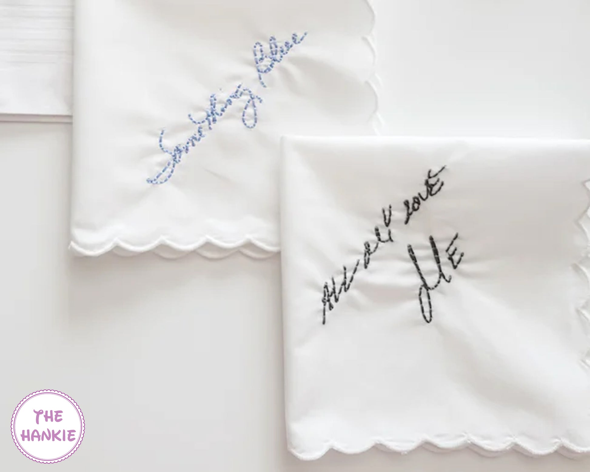 Two white handkerchiefs with embroidered text on a light background, featuring the brand 'The Hankie'.