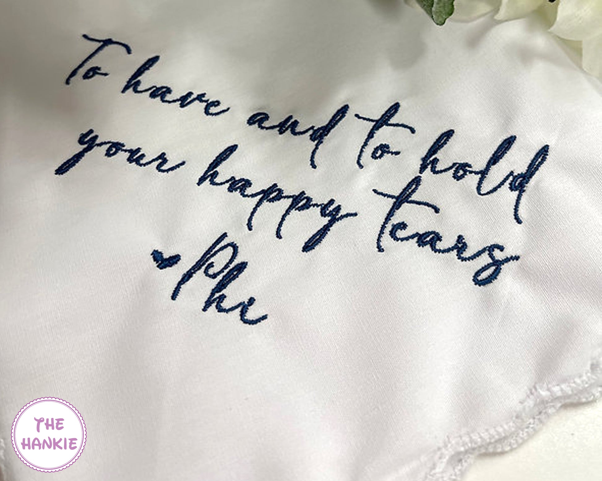 White handkerchief with blue embroidered text on a white background