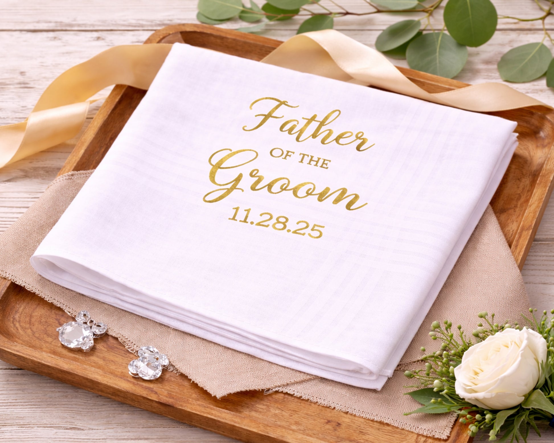White napkin with 'Father of the Groom' text on a wooden tray with decorative elements.