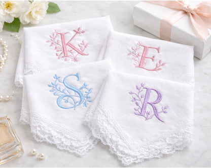 Set of white handkerchiefs with embroidered initials on a light surface.