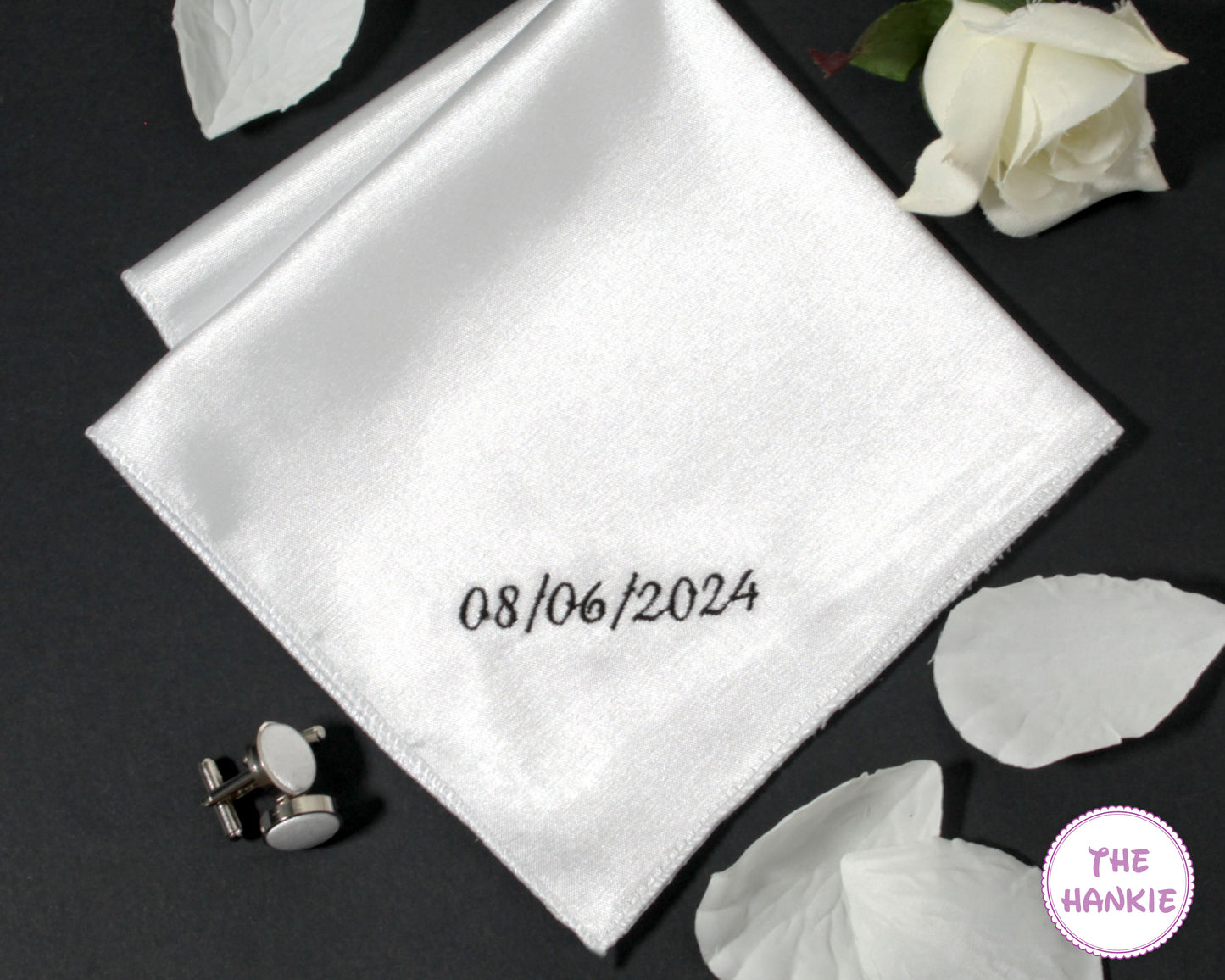 White pocket square with embroidered date, cufflinks, and white roses 