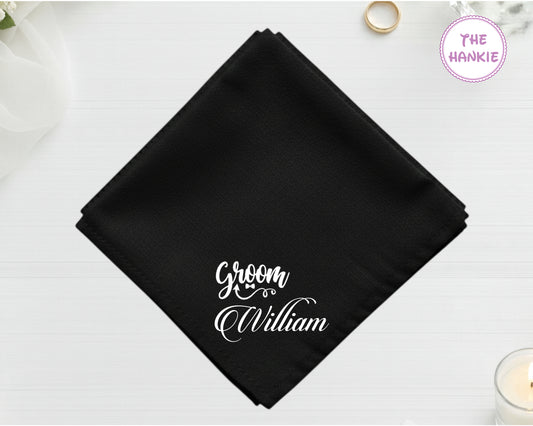 A midnight onyx black cotton handkerchief customized with "William" below a white vinyl "Groom" script design with a bowtie icon.